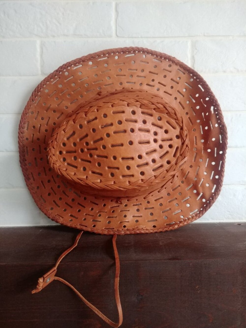 Brown leather cowboy hat with adjustable wire brim chin strap and cutout details